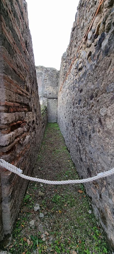 VI.7.18 Pompeii. December 2023.
Corridor to blocked doorway into VI.7.1, on west side of triclinium. Photo courtesy of Miriam Colomer.
