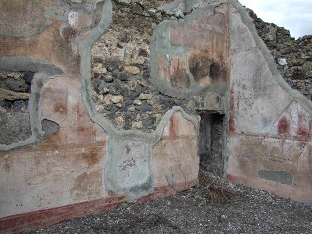 VI.7.19 Pompeii. December 2006. Detail of remains of painted plaster in north-east corner of oecus, with doorway into area below stairs.