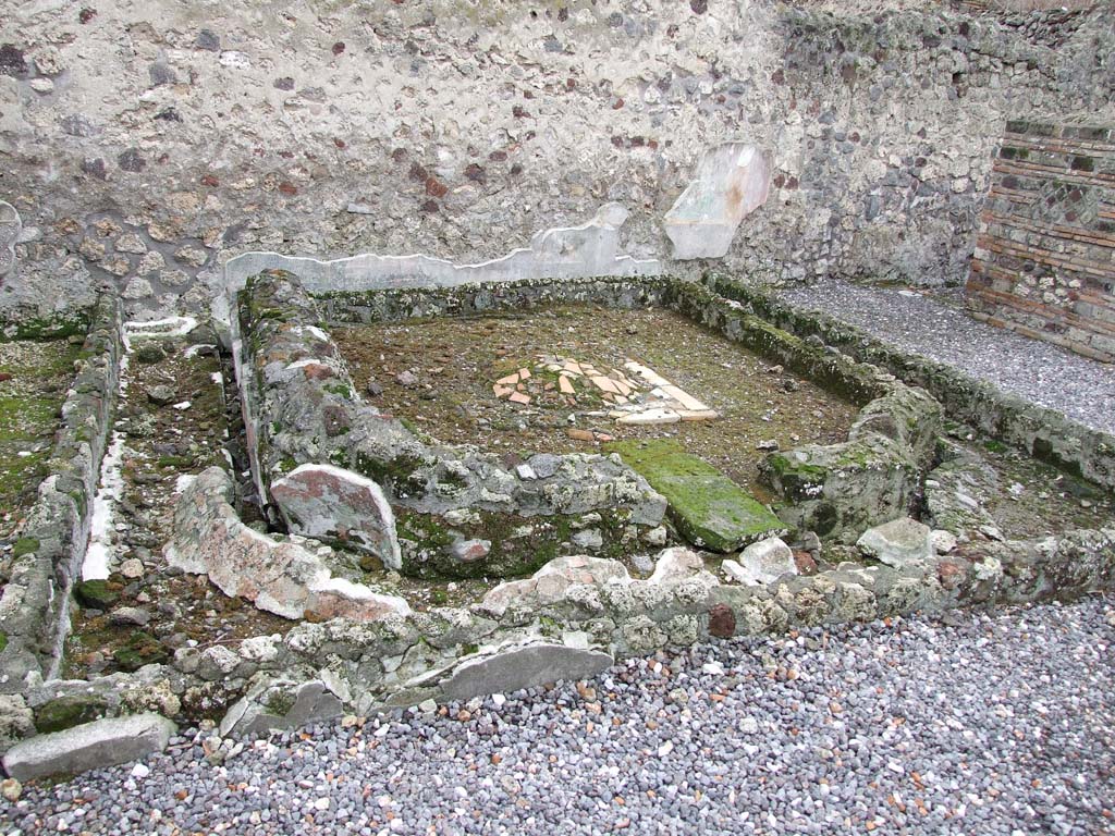 VI.7.23 Pompeii. December 2006. Remains of pyramidal fountain in courtyard.
According to Garcia y Garcia, this area was badly damaged due to the bombing during the night between the 14th and 15th September 1943.
The beautiful pyramid-shaped fountain was destroyed together with the partial destruction of the south wall including the beautiful garden painting with a painted statue of Diana. This was painted on the wall behind the fountain. Also destroyed were the dividing walls of the rooms on the west side of the area.
The damage was partially restored in 1976.
See Garcia y Garcia, L., 2006. Danni di guerra a Pompei. Rome: L’Erma di Bretschneider. (p.76)
See Jashemski, W. F., 1993. The Gardens of Pompeii, Volume II: Appendices. New York: Caratzas. (p.130-32).
