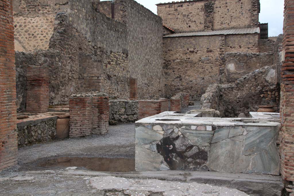 VI.8.8 Pompeii. April 2014. Looking north to entrance with three-sided marble counter with six urns and a hearth.
Photo courtesy of Klaus Heese.