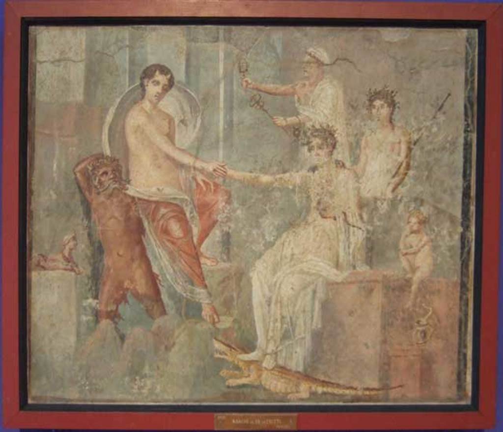 VI.9.1 Pompeii. Painting of the Arrival of Io at Canopus. From a room north of the atrium.
Io is depoasited on the rocks at Canopus carried by a river god, probably the Nile. She is being greeted by Isis. Behind Isis stand two figures, possibly Mercury and a priest. The small Harpocrates is to the right of the painting with his hand to his lips in the gesture of silence. To the left of the river god is a sphinx, and under Isis foot is a crocodile and a cobra. Now in Naples Archaeological Museum. Inventory number 9555. The house was named after this painting. See Zahn in BdI 1831 p. 18. See Helbig, W., 1868. Wandgemälde der vom Vesuv verschütteten Städte Campaniens. Leipzig: Breitkopf und Härtel. (139).