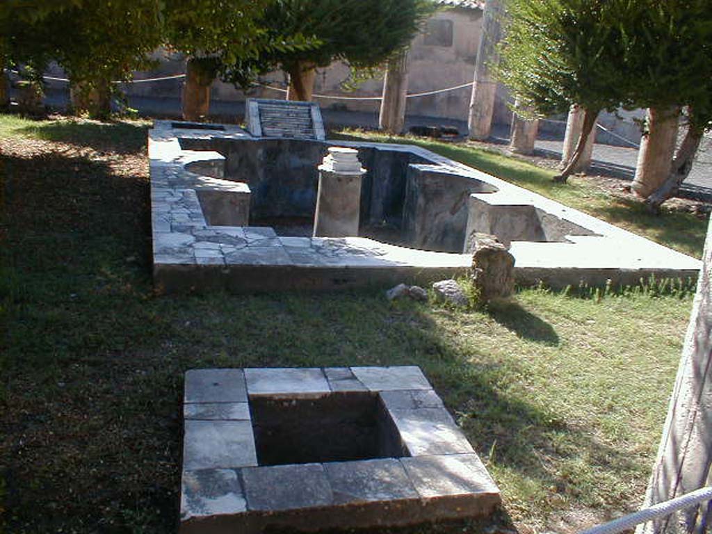 VI.9.2 Pompeii. September 2004. Peristyle garden 17, looking west across small pool 21, pool 18 and fountain 19.
According to Jashemski, the large and elaborate pool had its interior painted blue.
The interior walls were bordered with alternate rectangular and semi-circular recesses.
A column in the centre of the pool supported a round table, from which water jetted and fell into the pool.
There is a small pool 21 with a marble rim at the east end, together with a small basin 20 adjacent to the large pool on the west side.
The small basin may have been used for storing the fish while the pool was cleaned, or perhaps for cooling drinks.
See Jashemski, W. F., 1993. The Gardens of Pompeii, Volume II: Appendices. New York: Caratzas. (p.137-38)