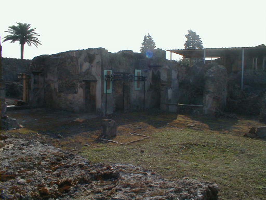 VI.9.5 Pompeii. September 2004.
South-east side of Corinthian atrium, on the left is the tablinum, in its south wall is a doorway to its neighbouring oecus.
The small entrance on the south side would have led to steps to the upper floor, followed by a small storeroom 25, and then a cubiculum 24, on the right.