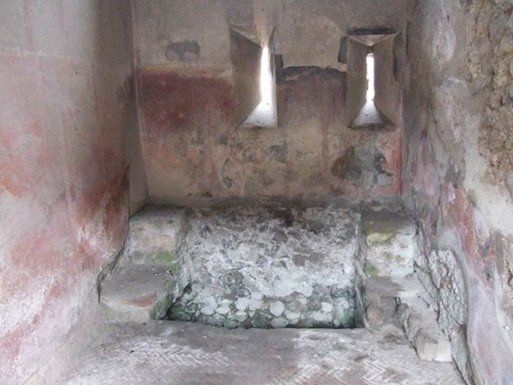 VI.9.6 Pompeii. March 2009. Room 18, large latrine near east wall of kitchen and latrine. According to Hobson, this latrine is just over one metre wide and would have had more than one seat. This would allow for “private” socialisation. See Hobson, B., 2009. Latrinae et foricae: Toilets in the Roman World. London; Duckworth. (p.80) He also states that this latrine possibly would have seated two or three persons. It had a high decorated dado, painted red, with yellow panels but without motifs. In the area above the dado, a garland of flowers is visible. The floor is a mixture of herringbone and oval tiling. See Hobson, B., 2009. Latrinae et foricae: Toilets in the Roman World. London; Duckworth. (p.86 and fig.110)