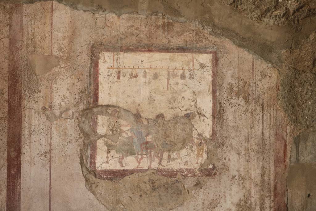 VI.10.1 Pompeii. December 2018.
Fresco on south wall of rear room showing people at a table with sausages, onions and other food hanging above them.
Photo courtesy of Aude Durand.