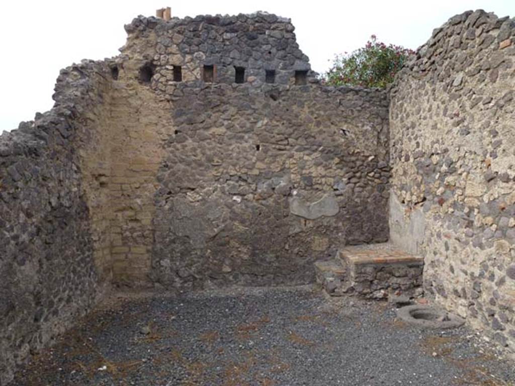 VI.14.6 Pompeii. September 2011. North wall of shop, with base of stairs in north-east corner, with cistern mouth nearby. In the upper level of the north wall, the holes for the support beams for the upper floor can be seen. Photo courtesy of Michael Binns.