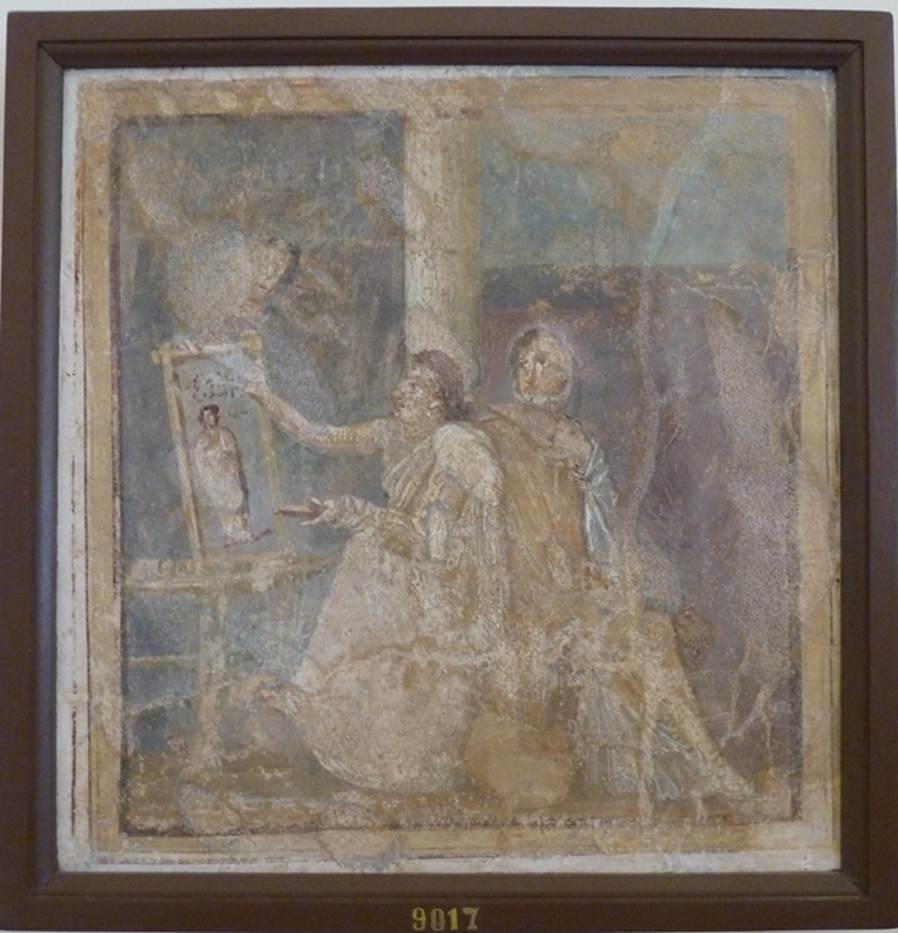 VI.14.42 Pompeii. Found in Cubiculum (3), the room on the south (or right) of the entrance corridor. Wall painting of woman painting.
She holds a palette in her left hand and is painting a picture on a table or easel with the right. A woman in yellow, with a white mantel over her shoulder, sits next to her. The woman admires the painting which is of a woman in a yellow robe. Now in Naples Archaeological Museum. Inventory number 9017. See Helbig, W., 1868. Wandgemälde der vom Vesuv verschütteten Städte Campaniens. Leipzig: Breitkopf und Härtel. (1444). See Richardson, L., 2000. A Catalog of Identifiable Figure Painters of Ancient Pompeii, Herculaneum. Baltimore: John Hopkins.
(p.120, he described it as a Genre scene with woman painting a picture, found in cubiculum 3, south of fauces).