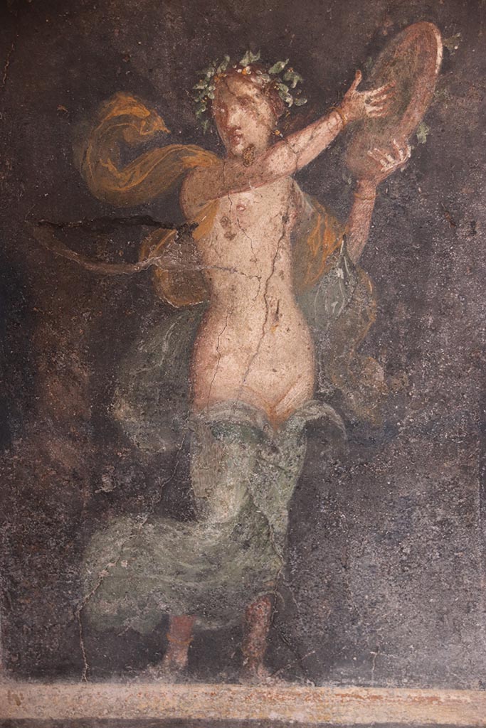 VI.15.1 Pompeii. October 2024.
Female figure of a Bacchante in zoccolo towards west end of north wall. Photo courtesy of Klaus Heese.