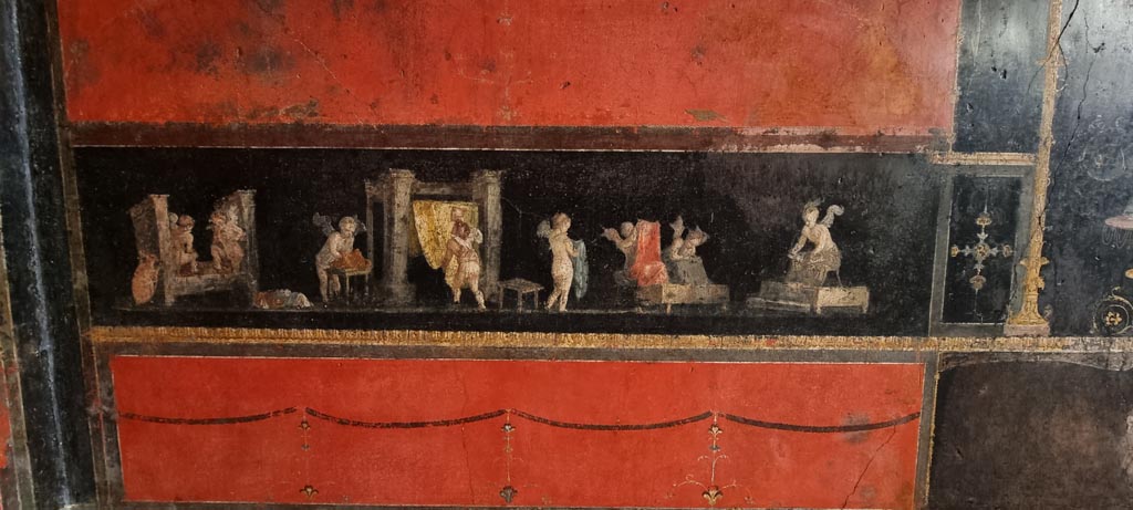 VI.15.1 Pompeii. January 2023.
East wall in north-east corner with panel showing cupids cleaning clothes in a fullery. Photo courtesy of Miriam Colomer.