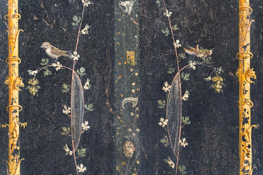 VI.15.1 Pompeii. August 2023.
Detail of painted decoration from above base of painted candelabra on east wall at north end. Photo courtesy of Johannes Eber.
