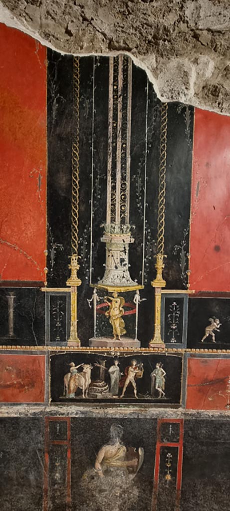 VI.15.1 Pompeii. January 2023.
East wall with painted panel of Apollo and Diana after the killing of the python.
Underneath is a standing figure of an Amazon armed with a shield.
Photo courtesy of Miriam Colomer.