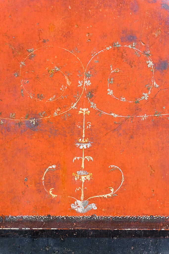 VI.15.1 Pompeii. August 2023.
Painted detail from red panel above black predella on east wall at south end.
Photo courtesy of Johannes Eber.