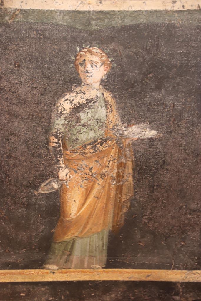 VI.15.1 Pompeii. October 2023.
Zoccolo on south end of east wall with painted panel of female figure holding plate with offerings. Photo courtesy of Klaus Heese.