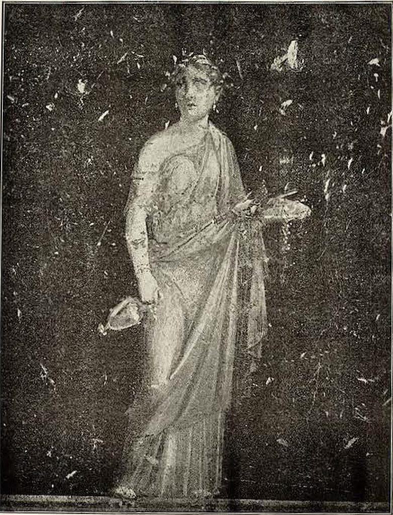 VI.15.1 Pompeii. Painted panel on zoccolo (0.49 high) from east wall at south end.
Described by Sogliano as –
“Figura muliebre: coronata di alloro e vestita di chitone verde, con manto giallo, tiene nella destra abbassata il prefericolo e con la sinistra un piatto con le offerte, tra cui una pina”
(Female figure: crowned with laurel and dressed in green robe with yellow mantle, holding a vase with a handle lowdown in her right hand and a plate with offerings, including a pine cone, in her left.)
See Sogliano, A. La Casa dei Vettii in Pompei, in Mon. Ant. 1898. (p.383-384, fig. 68).
