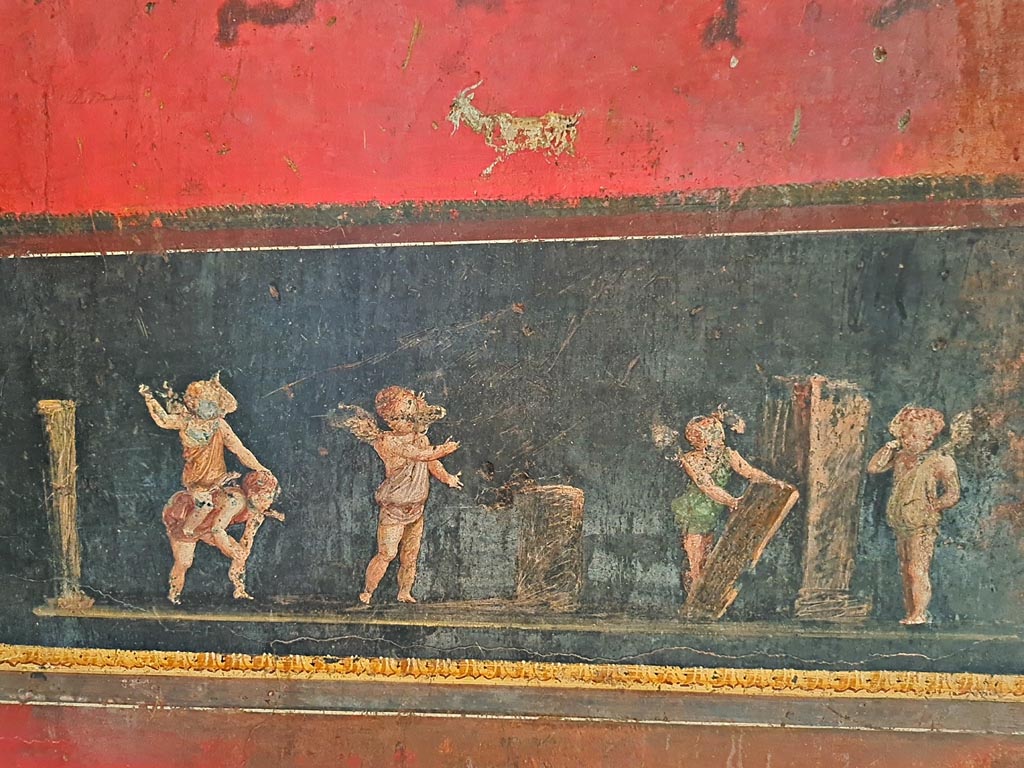 VI.15.1 Pompeii. April 2023.
Detail of cupids from south wall in south-east corner, taking part in an archery or throwing contest. Photo courtesy of Giuseppe Ciaramella