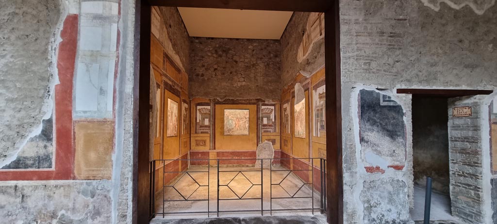 VI.15.1 Pompeii. January 2023.
East wall in south-east corner of peristyle with doorway to exedra, in centre, and into room o, on right. Photo courtesy of Miriam Colomer.