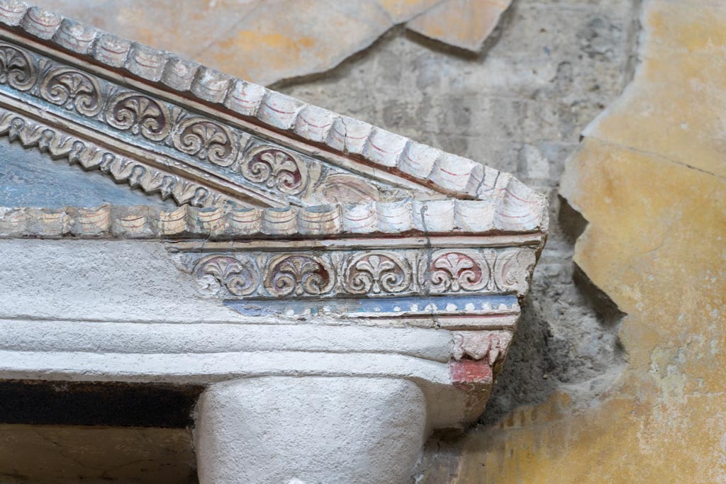 VI.15.1 Pompeii. March 2023.
Detail of stucco decoration on north end of aedicula against west wall in services area. Photo courtesy of Johannes Eber.
