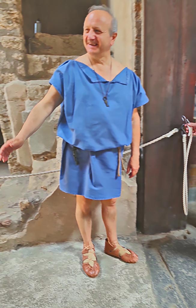 VI.15.1 Pompeii. 8th June 2024. Actor dressed in costume, “Come in”.
Historical reconstruction entitled L’altra Pompei prende vita (The other Pompeii comes to life).