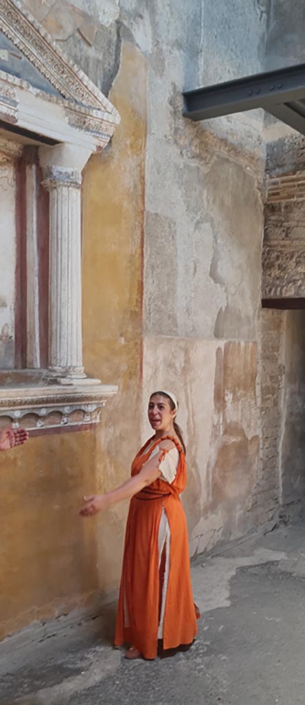 VI.15.1 Pompeii. 8th June 2024.
Actress playing part of slave in front of household lararium.
Photo courtesy of Giuseppe Ciaramella.
Historical reconstruction entitled L’altra Pompei prende vita (The other Pompeii comes to life).