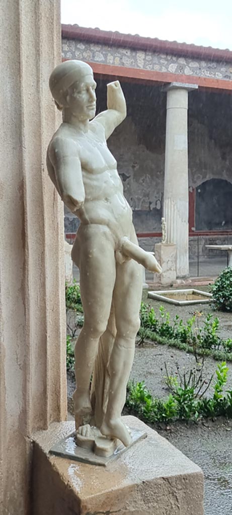 VI.15.1 Pompeii. January 2023.
Statue of Priapus displayed on east side of peristyle. Photo courtesy of Miriam Colomer.
According to Sogliano –
“Found in the kitchen were two marble statues, both of which without doubt belonged to the decoration in the peristyle.”
See Sogliano, A. La Casa dei Vettii in Pompei in Mon. Ant. 1898, (p.269).