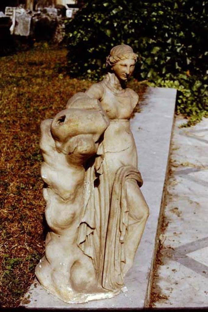 VI.15.5. Pompeii. 1971. Marble fountain statuette of a standing nymph. Photo by Stanley A. Jashemski.
Source: The Wilhelmina and Stanley A. Jashemski archive in the University of Maryland Library, Special Collections (See collection page) and made available under the Creative Commons Attribution-Non Commercial License v.4. See Licence and use details.
J71f0293
According to Wilhelmina, “found inside the niche was a white marble puteal, covered with a grey marble plate on which stood a marble fountain statuette of a standing nymph (0.54m high, Naples Archaeological Museum inv.no: 124 841) leaning with her left arm on a leather bag placed on top of a trunk of a tree.
The statuette still showed traces of colour. There were various statuettes nearby.”
See Jashemski, W. F., 1993. The Gardens of Pompeii, Volume II: Appendices. New York: Caratzas. (p.156)