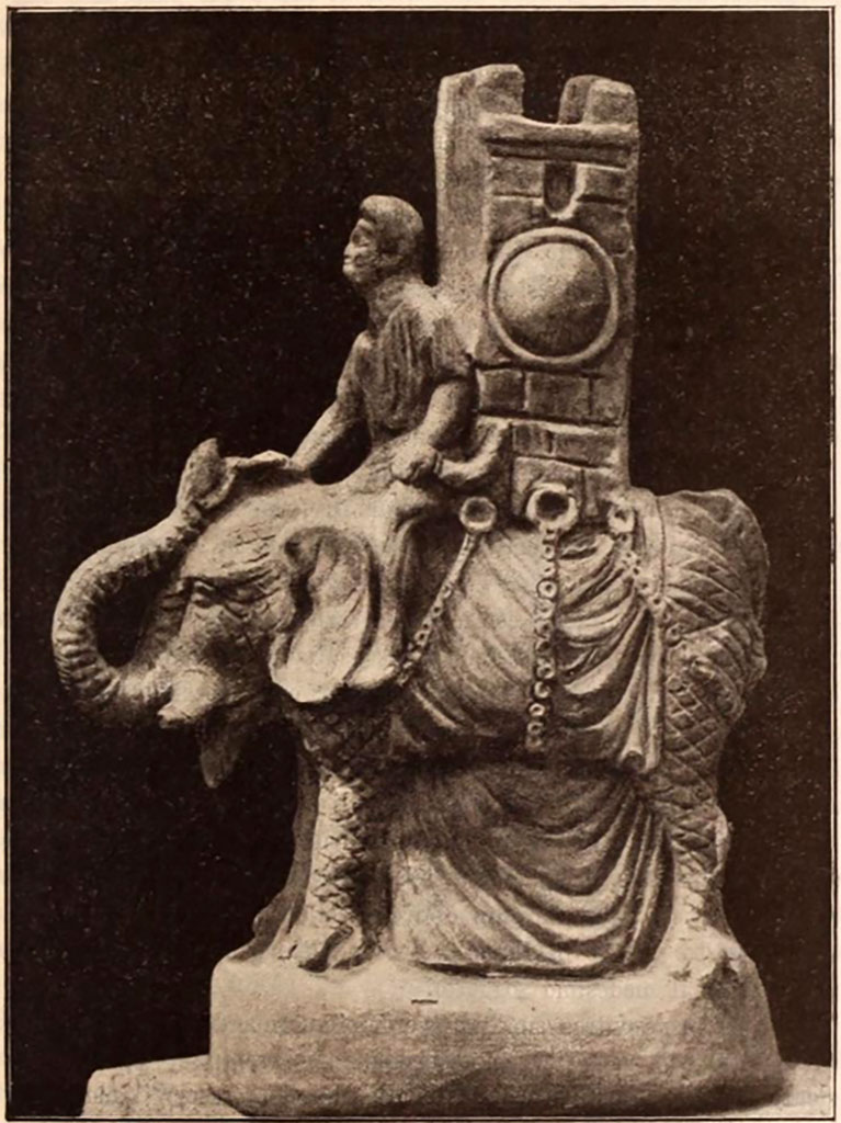 VI.15.5 Pompeii. Clay figurine of an elephant carrying a tower on its back, 0.35m high incl. base.
The figurine served as a vessel for liquid.
The liquid was put in through the top of the tower, which was open.
See Notizie degli Scavi di Antichità, 1897, p.25, fig. 3.
It was found in October 1895 in or near the garden niche, together with a group of other objects.
See Notizie degli Scavi di Antichità, 1895, p.438.
According to Jashemski, this was also a jug, and was now in the Naples Archaeological Museum, inventory number 124845, Ruesch 442.
See Jashemski, W. F., 1993. The Gardens of Pompeii, Volume II: Appendices. New York: Caratzas. (p.155)