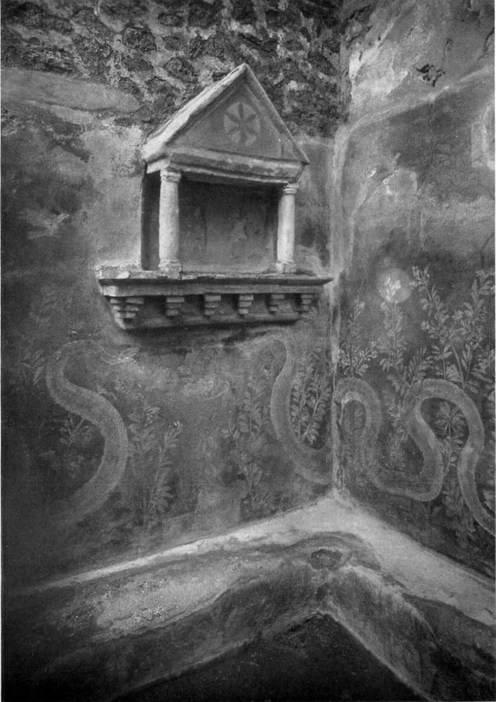 VI.15.23 Pompeii. 1930s? Kitchen in south-west corner of peristyle.
Lararium in north-west corner of kitchen, near doorway to south portico.
Boyce said, against the wall below the aedicula and that of the entrance doorway was a masonry seat (h.0.30).
It was decorated upon a background of red with painted luxuriant foliage which covered the front surface of the bench.
It extended above the bench to form a background for the serpents.
See Boyce G. K., 1937. Corpus of the Lararia of Pompeii. Rome: MAAR 14. (p.56, no.219, and Pl.15, 1 and 2)
