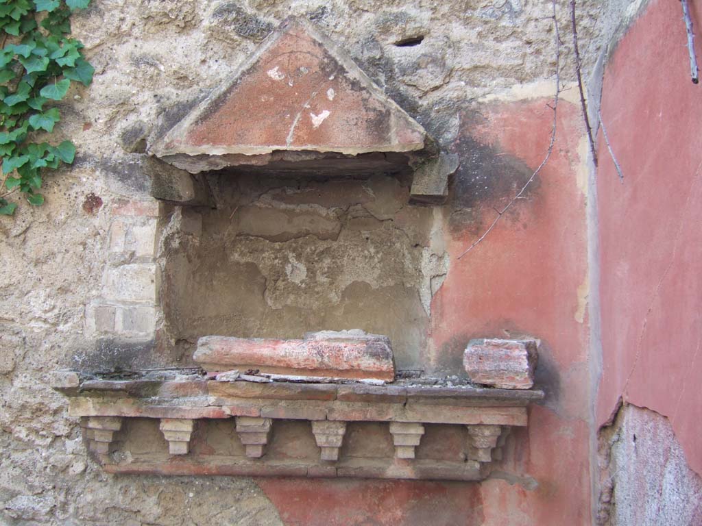 VI.15.23 Pompeii. September 2005. Lararium.
According to Boyce, the three rooms in the south-west portion, to the right of the entrance, have bare walls without any decoration.
The kitchen in the corner is the exception, with the lararium on the west wall, in the north-west corner.
In the kitchen, the hearth is built against the west wall and between it and the north wall is the lararium.
A heavy ledge, held by consoles projecting from the wall, supported a temple façade constructed before a semicircular niche with flat ceiling.
The façade consisted of two Doric columns with bases and capitals, an architrave and a pediment.
The ledge and the aedicula were constructed of a mixture of brick and tufa.
The whole was painted red except for a star on a white ground in the centre of the tympanum.
See Boyce G. K., 1937. Corpus of the Lararia of Pompeii. Rome: MAAR 14. (p.56, no.219, and Pl.15, 1 and 2)
See Fröhlich, T., 1991. Lararien und Fassadenbilder in den Vesuvstädten. Mainz: von Zabern. (L73 and Pict. 35,3)
See Giacobello, F., 2008. Larari Pompeiani: Iconografia e culto dei Lari in ambito domestico. Milano: LED Edizioni. (p.183)