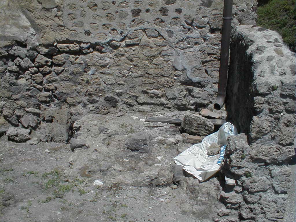 VI.16.6 Pompeii. May 2005. North-east corner of fullonica, with structure, possibly remains of tub or basin.
According to Sogliano, the walls were undecorated at the bottom to the height of the dado, and then above were crudely painted in white.
Leaning against the north wall would have been a wooden ladder, which probably led up to some rooms at the top of the House of the Golden Cupids.
Also against the north wall were a masonry structure with two steps.
To left were the remains of three low walls, arranged like fullonica tanks for treading pigment into cloth.
There were also the remains of a shallow tank.
See Notizie degli Scavi di Antichità, 1906, p. 350.