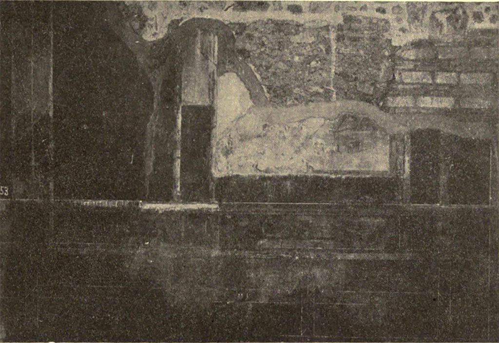 VI.16.7 Pompeii. c.1906. Room B, south wall showing painted decoration.
According to NdS, this south wall was the best preserved of the walls in the atrium.
It was divided into five large panels, however the one to the right was only a part-panel due to the doorway.
The larger central panel had a black background, whereas the others were painted red.
Only the lower part of the central painting (see above) was conserved (0.50m high x. 1.25m wide).
On a rock, on the right, sat a male figure, but only his left very dark leg remained.
His foot was fitted with a high boot with laces.
Leaning against the rock was a panpipe.
Nearby to the right, on the green pastureland were two lambs and a goat, forming a group; two goats formed another group on the left.
It was probable that the painting showed Paris grazing the flock on Ida.
See Notizie degli Scavi di Antichità, 1906, p.376-7, fig.2.