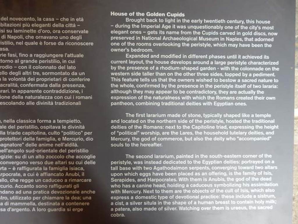 VI.16.7 Pompeii. May 2016. Information card. Photo courtesy of Buzz Ferebee.
“The second lararium, painted in the south-eastern corner of the peristyle, was instead dedicated to the Egyptian deities: portrayed on a tall base with two serpents, converging towards two altars upon which eggs have been placed as an offering, is the family of Isis, Serapides and Harpocrates. With them is Anubis, the god of the dead who has a canine head, holding a caduceus symbolizing his assimilation with Mercury. Next to them are the objects of the cult of Isis, which also express a domestic type of devotional practice: these include a sistrum, a cist, a silver situla in the shape of a human breast to contain holy milk, and a patera also made of silver.
Watching over them is Uraeus, the sacred cobra.”