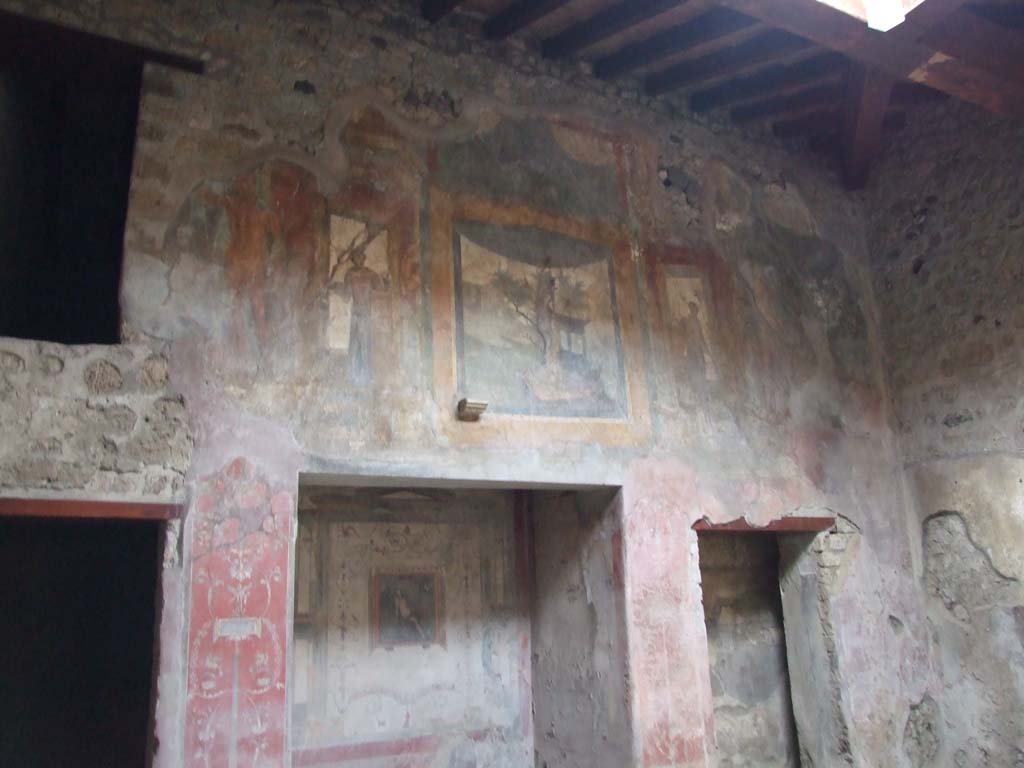 VI.16.15 Pompeii. December 2006. West wall of atrium B, detail of upper wall paintings.
Architectural painting with blue curtain, sacred landscape and at the extremities, statues of Poseidon and Nike.