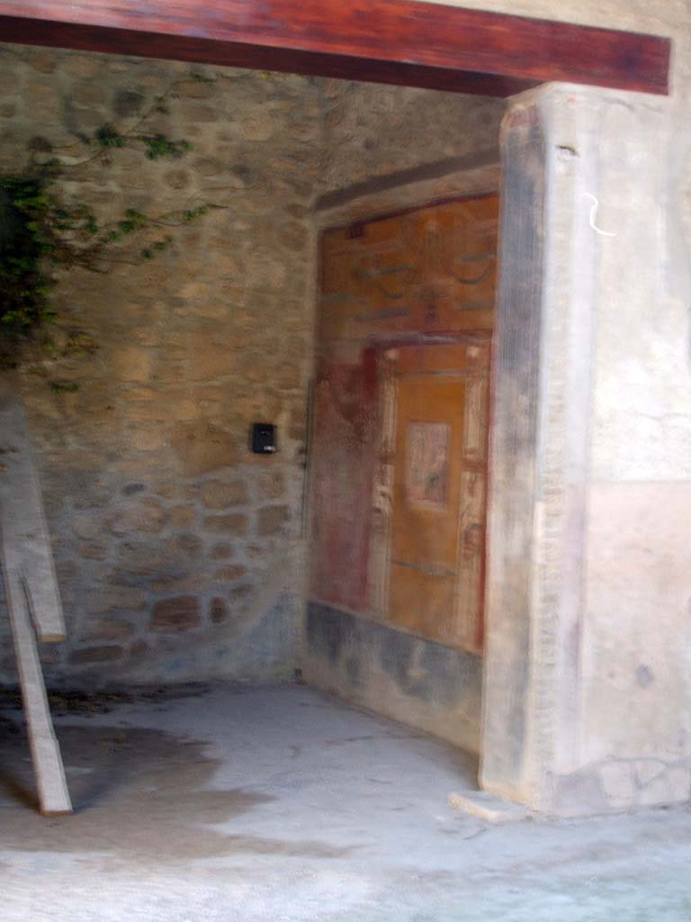 VI.16.15 Pompeii. May 2005. Looking south-west to doorway of room F.
Both the west and east wall were painted symmetrically.
Each wall was divided into three panels with yellow frieze and black dado.
At the top was a painted stucco cornice.
Each central panel was painted yellow, and both had a picture painted in the centre.