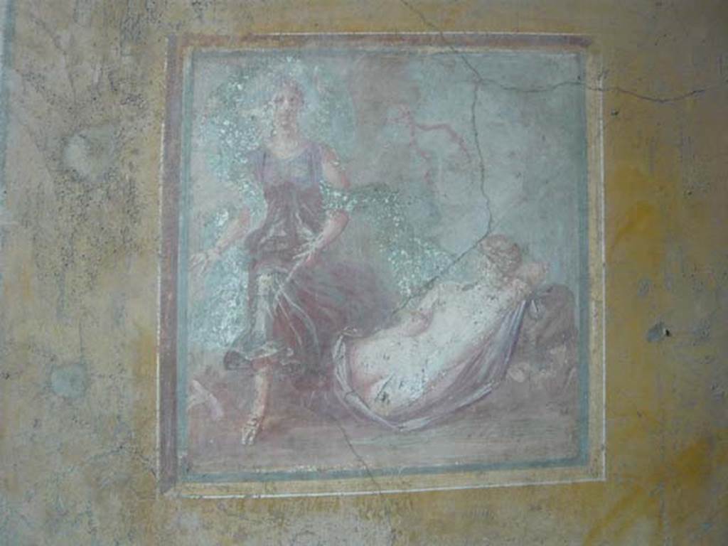 VI.16.15 Pompeii. May 2012.
Wall painting of The Sleeping Ariadne from the centre of the east wall of room F. Photo courtesy of Buzz Ferebee.
Kuivalainen describes –
“A composition of two figures. In the foreground a sleeping almost naked female figure, with her back to the viewer; she is reclining on a stone, with her right arm supporting her head; she lies on a purple cloak which covers her legs; she has gold arm rings, and her hair is fair. On the left, another figure steps energetically over the legs of the sleeping figure. He wears sandals and a purple robe with wide drapery, and a flaring blue cloak; he carries a thyrsus with a red ribbon and possibly a bunch of leaves on top under his left arm; his head is slightly turned to the left, and his long curly hair is darkish.”
Kuivalainen comments –
“Sleeping Ariadne callipyge discovered by an effeminate Bacchus. The shadowing on his skin is broader and darker than the female’s. The flaring cloak resembles that of Bacchus, e.g. in the Casa del Citarista (E7), referring to velificatio and to the epiphany of the divinity.”
See Kuivalainen, I., 2021. The Portrayal of Pompeian Bacchus. Commentationes Humanarum Litterarum 140. Helsinki: Finnish Society of Sciences and Letters, (p.143, E3).