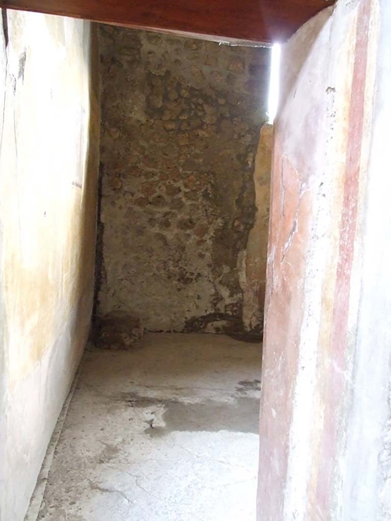 VI.16.15 Pompeii. December 2006. Looking south into doorway to room G in south-west corner of atrium.
According to NdS, the triclinium, although small, was rectangular with a rough floor of cocciopesto.
At the time of the disaster it was receiving a more dignified decoration.
Opening in the upper part of the south wall was a window with well-preserved iron grating.