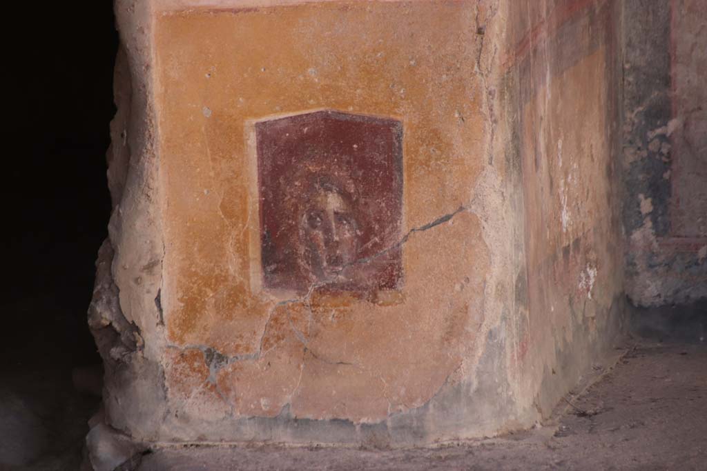 VI.16.15 Pompeii. September 2021.
Base of painted pilaster with mask on west side of atrium with doorway to room C, on left. Photo courtesy of Klaus Heese.