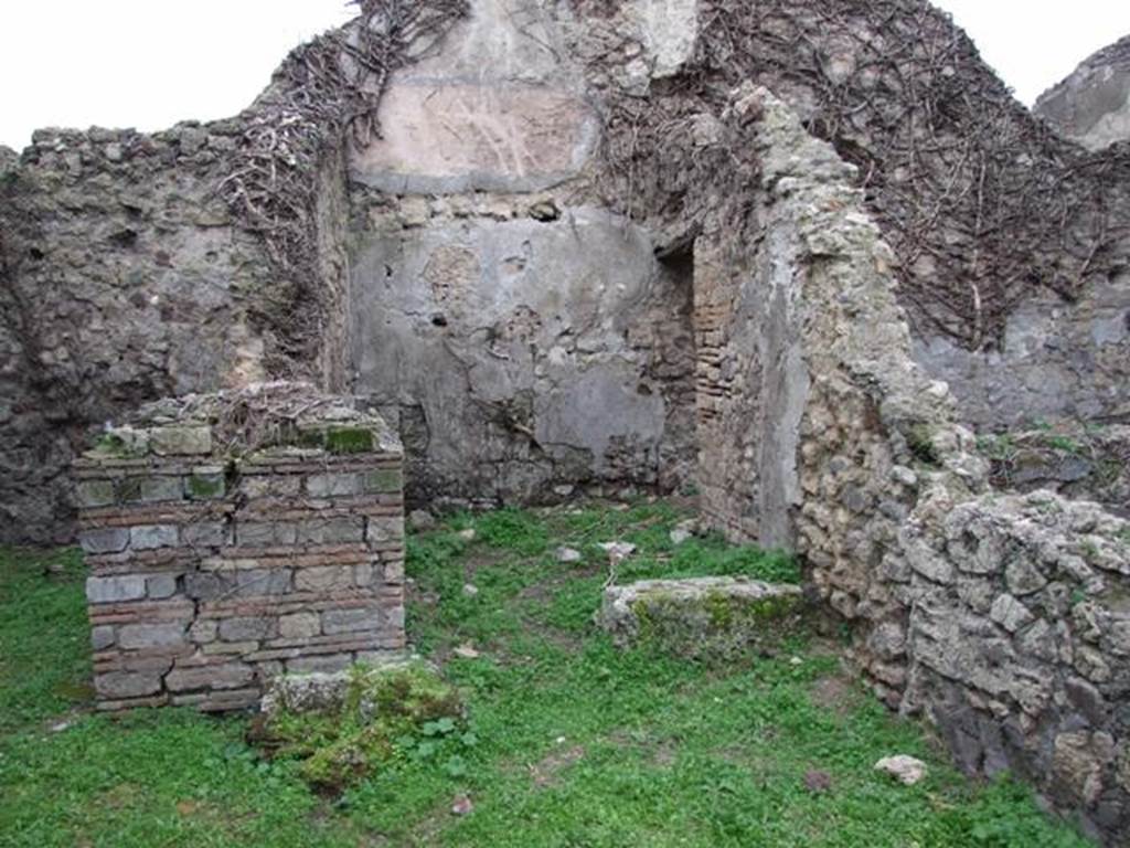 VI.16.18 Pompeii. December 2007. Doorway to rear room in centre, with doorway to rear room on north side. According to NdS, this room contained a limestone boulder that was used to form the first rung of a wooden staircase to the upper floor. The walls of the room were bare and unpainted and the floor was of opus signinum. In the heights of the north and west walls could be seen the white plaster of the upper room. A small doorway, with large threshold made of pieces of lava, at the left end of the north wall led into a small room.