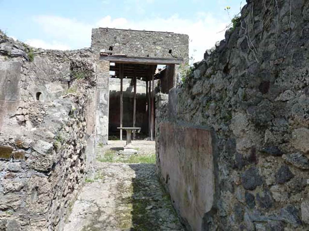 VI.16.28 Pompeii. May 2010. Looking east along fauces A, to atrium C. The floor was made of cocciopesto, in which was buried some pieces of marble without a design. The south wall preserved a high dado on a blackish background, finishing above with a wide red frieze.
Under the frieze was a simple coating of rough white plaster. Found on the south wall, shown here on the right, was a graffito MVSQ?N . Above on a coarse white plaster, in rather large letters was COPONII. From this graffito of Coponii, the house gained one of its names. See Notizie degli Scavi di Antichità, 1908, p. 271.