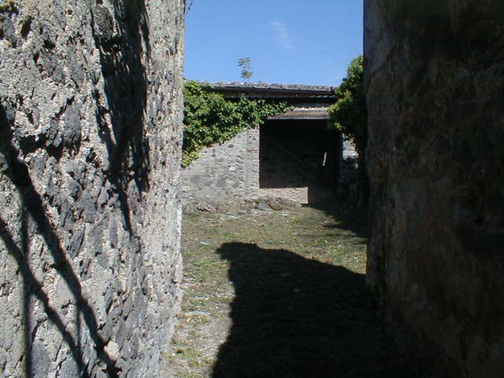 VI.16.29 Pompeii. September 2004. Looking east from fauces A, towards atrium B.
According to NdS, the atrium was without an impluvium.
The walls were similar to the entrance corridor, being entirely white except for the lower dado which was blackish.
Above the dado were the remains of part of the imitation buried slabs of white marble.
Immediately above the plinth, in the space between two red bands, were paintings of various types of birds feeding near to plants and fruit.
In the high part left of the east wall were two semi-circular niches built into the wall, and in the middle of the same wall was a large window.
In the south-east corner of the atrium was a hearth.