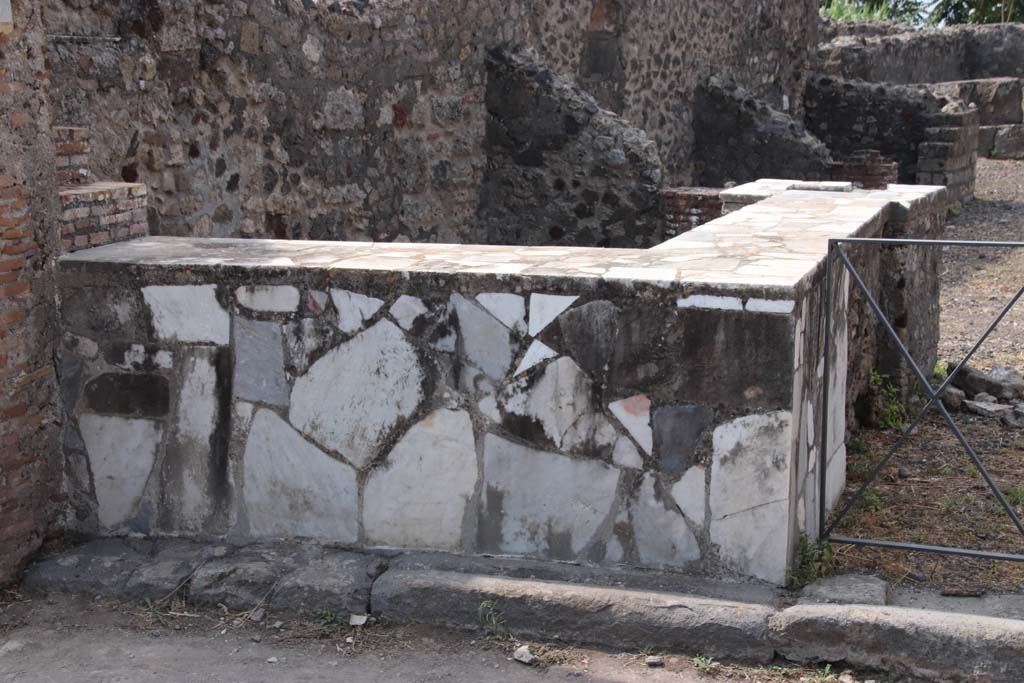 VI.17.4 Pompeii. September 2021.
Looking west along south wall with two-sided marble counter with hearth and display shelves. Photo courtesy of Klaus Heese.