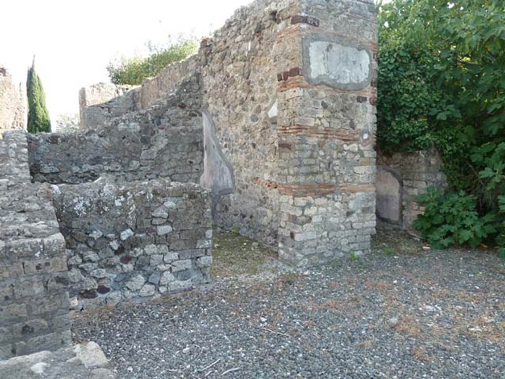VI.17.10 Pompeii. September 2015. South side of atrium, with two of the three doorways to cubicula. According to Allroggen-Bedel –
The room described by La Vega, as No.10, corresponded to the preserved remains in the middle room left from atrium, doorway on right of photo.
According to La Vega –
“From the 9th to the 17th November we excavated this room, which had a floor of black mosaic with white border all around, and white rosettes sprinkled throughout, and it was found patched up by the ancients at a site close to the threshold. The plaster was painted with following format: Red zoccolo with a few lines, and large fronds of herbs, the panels above were yellow with vases/pots in the middle, the bands that one could distinguish were red, decorated with grotesque architecture: the decoration above had a white background with various bands and grotesque architecture. On one side of this room, there was in the wall, an undercut recess that ends with the floor. It was preserved without lifting a piece. (Si e conservato senza levarci alcun pezzo).”