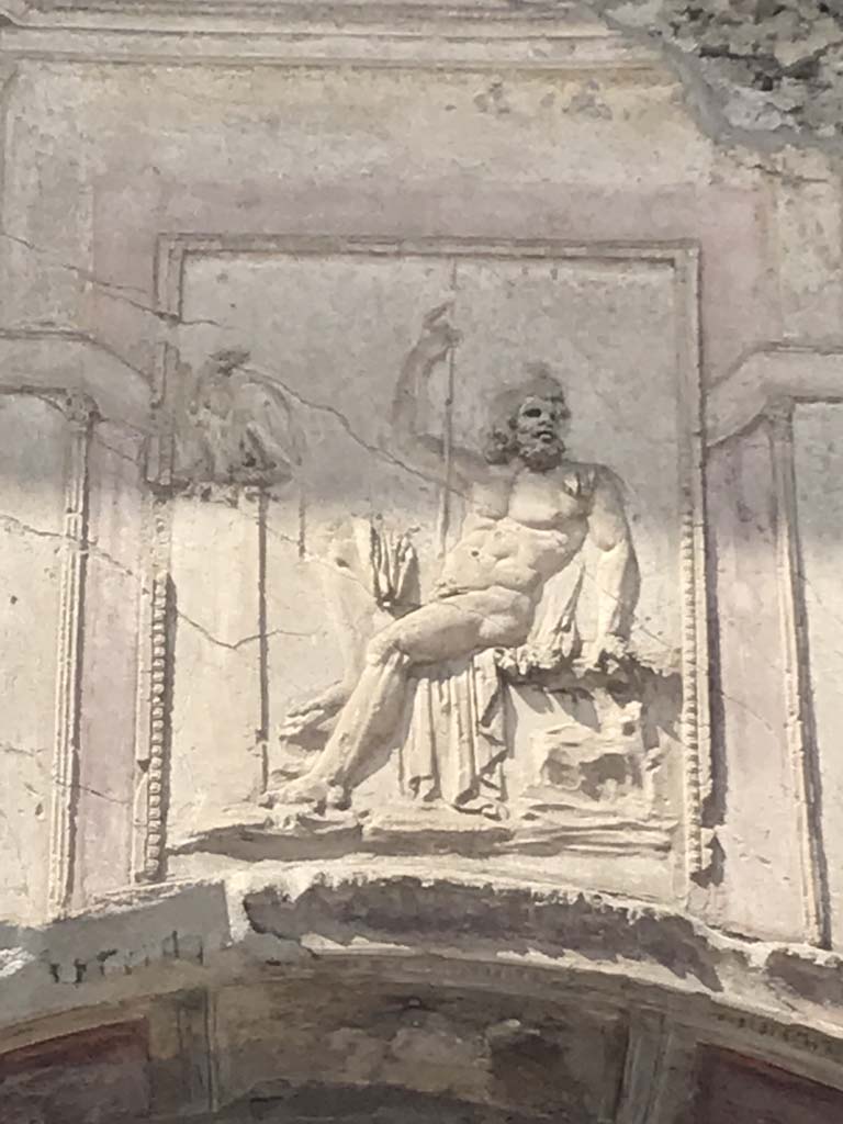 VII.1.8 Pompeii. April 2019. Detail of stucco relief of a seated Zeus, above arch of nymphaeum F.
Photo courtesy of Rick Bauer.