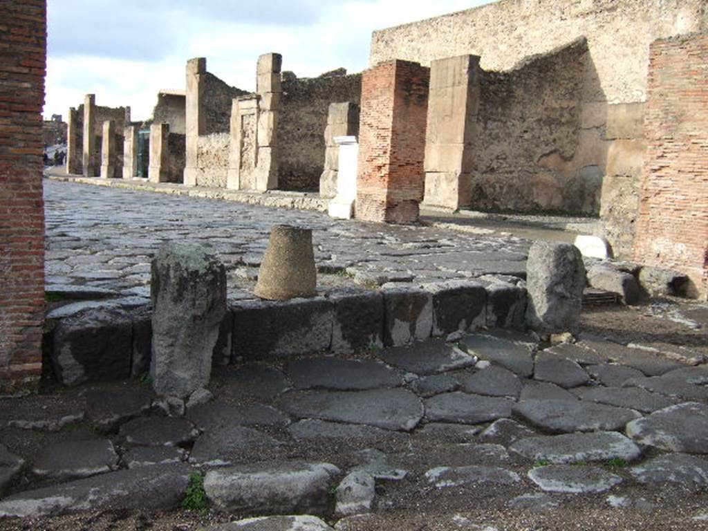 Looking west along Via dell’ Abbondanza, Pompeii. VII.1.12 is first shop on right, near where the statue of Holconius Rufus was found (the white marble pedestal).