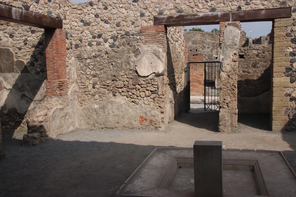 VII.1.25 Pompeii. October 2023.
Looking east across impluvium in atrium 24 to fauces 23 and entrance VII.1.25. Photo courtesy of Klaus Heese.