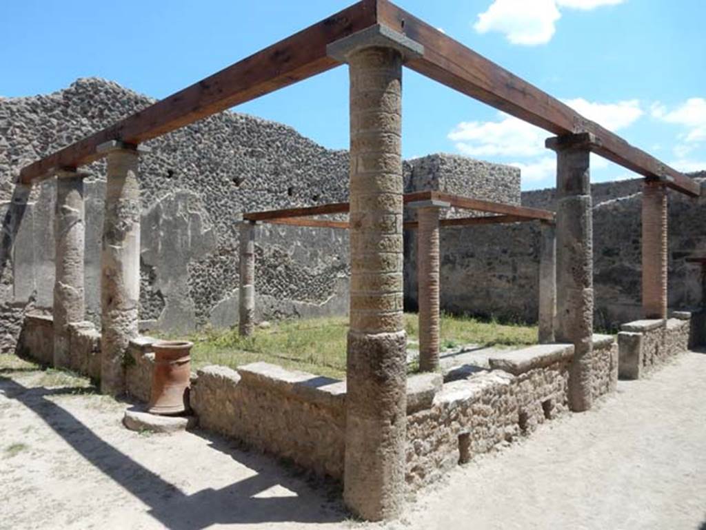 VII.1.47 Pompeii. May 2017. Looking south-east across peristyle 19. Photo courtesy of Buzz Ferebee.
According to Jashemski –
The peristyle garden at the rear of the tablinum of the house at entrance 47 was enclosed on the west and north by a portico supported by five columns which were joined by a low wall, with an entrance to the garden on the west.
Both the mouth of a cistern (on the north) and a terracotta puteal (on the west) were incorporated into the low wall.
The four small columns in the garden probably supported a pergola which shaded a wooden triclinium.
See Jashemski, W. F., 1993. The Gardens of Pompeii, Volume II: Appendices. New York: Caratzas. (p.169-71.
According to Soprano –
Ubicazione: giardino.
Bibliog. Fiorelli, op. c, p.180; idem Scavi di Pompei dal 1872, p.12;
Breton, op. c. p.317; Overbeck, op. c, p.286.
Al centro del giardino s’innalzavano quattro piccole colonne che probabilmente sostenevano il pergolato di letti tricliniare in legno.
See Soprano, P. (1950). I triclini all’aperto di Pompei. (In Pompeiana, raccolta di studi per il secondo centenario degli scavi di Pompei. Napoli, Gaetano Macchiaroli, Editore, P. 308, no.34).