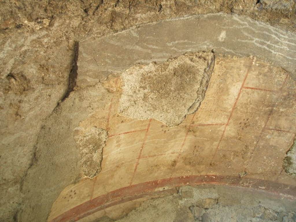VII.2.7 Pompeii. Shop. May 2005. Small remains of painted plaster in arched niche under masonry staircase on north wall. The arch was outlined in red on a white background with a dotted rosette in each of the painted squares.