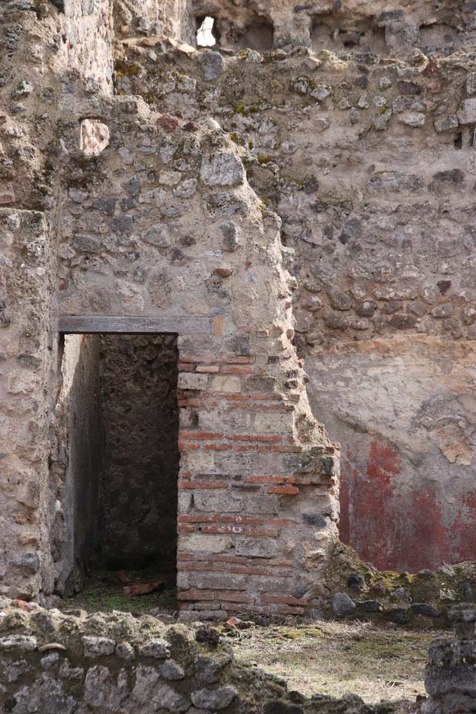 VII.3.8 Pompeii. October 2020.
Looking south across room “c” towards doorway to latrine “f”, and small cubiculum “d” with red painted plaster.
Photo courtesy of Klaus Heese.