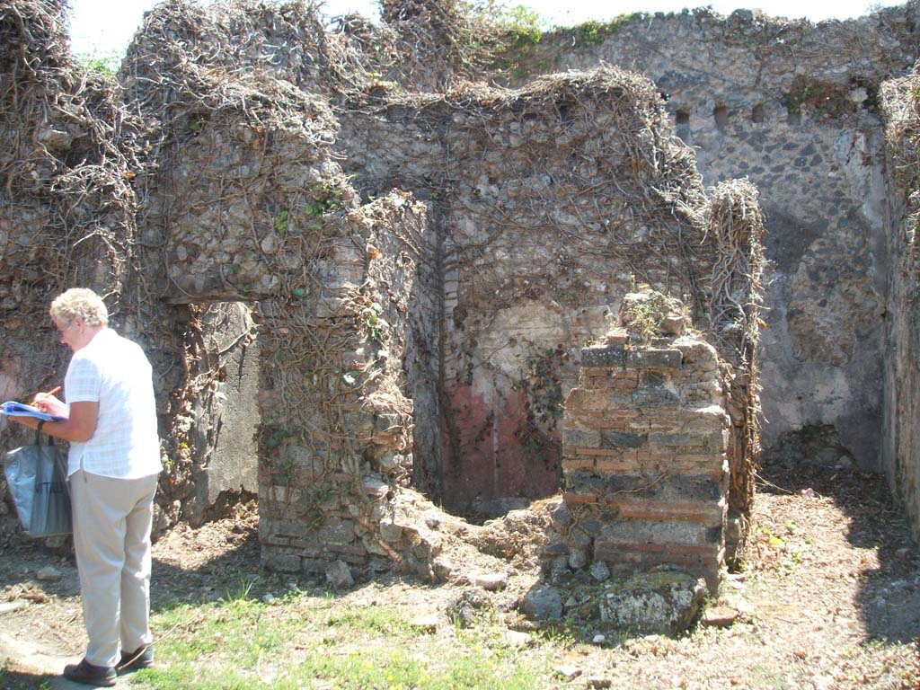 VII.3.8 Pompeii. May 2005.
Looking south. Doorway to latrine “f”, small cubiculum “d” with red painted plaster and corridor to large rear room “e”.