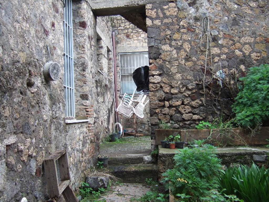 VII.3.24 Pompeii. Looking north from entrance. According to Fiorelli, this was a workshop that was part of the house next-door. This area had two furnaces, one basin and a hearth all mostly destroyed. The latrine was next to the entrance, together with a small room. Then, through the doorway with the two steps (possibly modern), was the atrium.
On the south side of the atrium were stairs to the upper floor, and on the north side was a cubiculum.
See Pappalardo, U., 2001. La Descrizione di Pompei per Giuseppe Fiorelli (1875). Napoli: Massa Editore. (p.87)