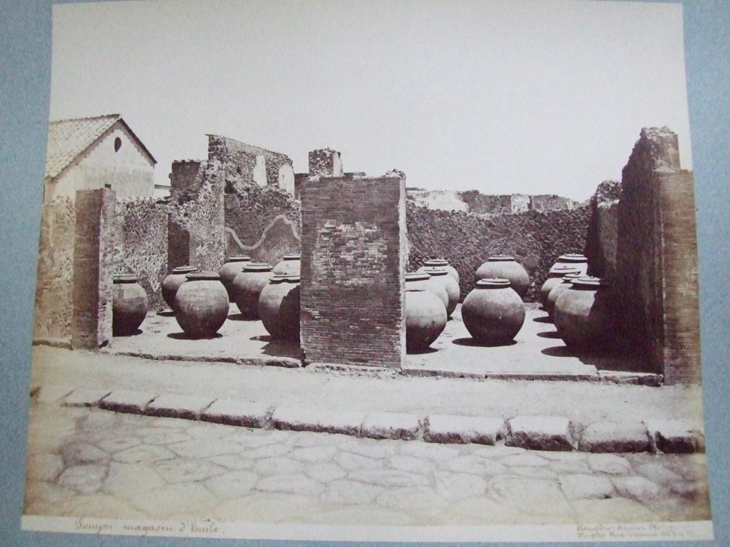 VII.4.13 Pompeii and VII.4.14. Via Foro oil shop. 19th century photograph by Amodio.
Photo courtesy of the Society of Antiquaries, Fox Collection.
Fiorelli says the two adjacent large shops had these dolia temporarily deposited in them.
They had come from outside Pompeii near “il Sarno”.
Some of these are now to be found outside the city wall below the Temple of Venus and the Sarno Baths.
See Pappalardo, U., 2001. La Descrizione di Pompei per Giuseppe Fiorelli (1875). Napoli: Massa Editore. (p.89).